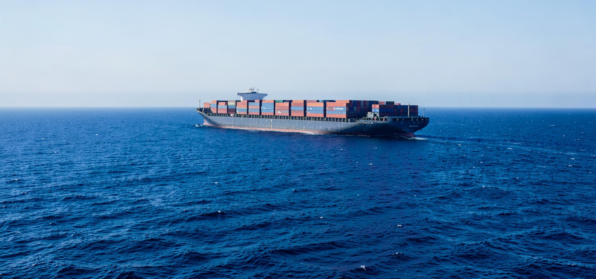 Container ship carrying export cargo across the open blue sea